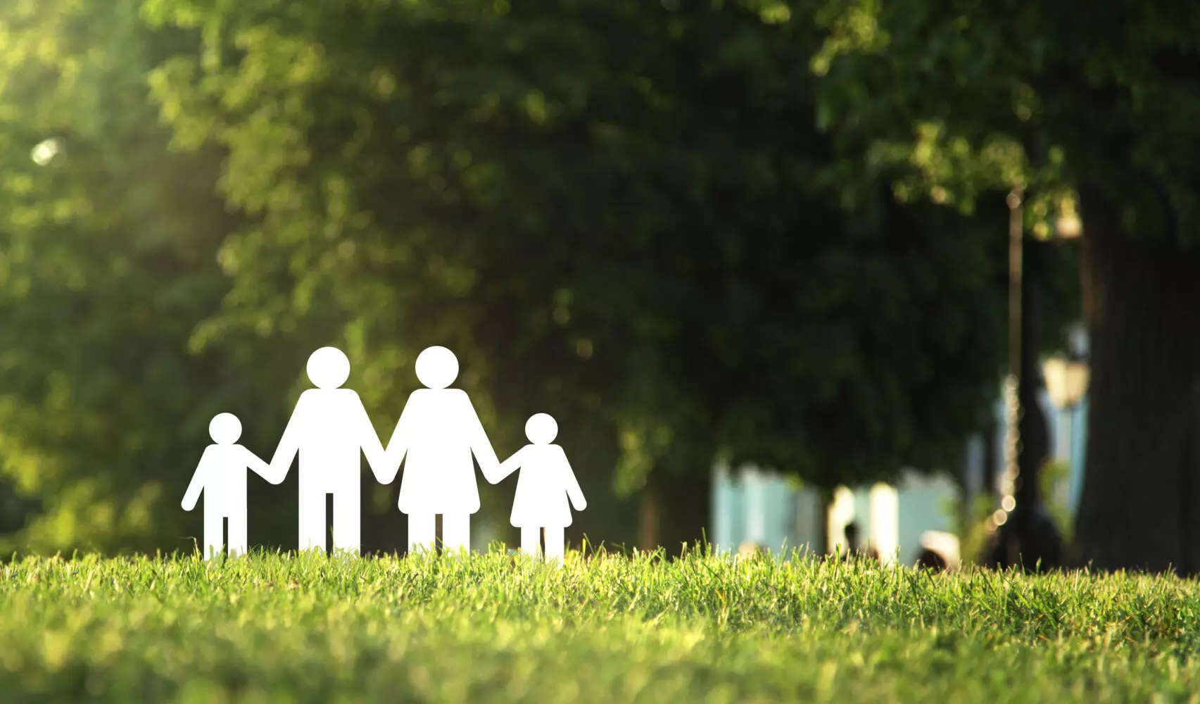 Rappresentazione stilizzata di una famiglia composta da due adulti e due bambini, che si tengono per mano in un parco verdeggiante, immersi nella natura.